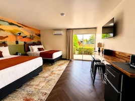 Habitación de hotel con dos camas, un escritorio, un televisor de pantalla plana y vistas a zonas verdes.