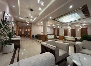 A modern hotel lobby with seating areas, a reception desk, and a large chandelier. - The Bodhi Tree (Leh)