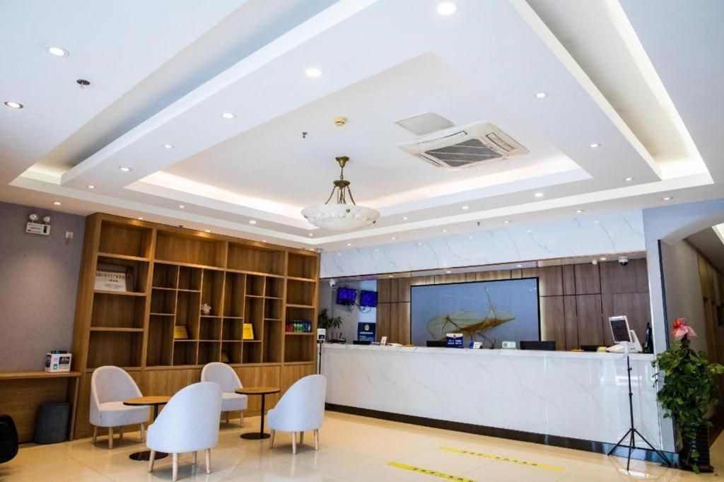 A hotel reception area with a marble counter, wooden shelving, and seating.