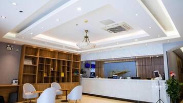 A hotel reception area with a marble counter, wooden shelving, and seating.