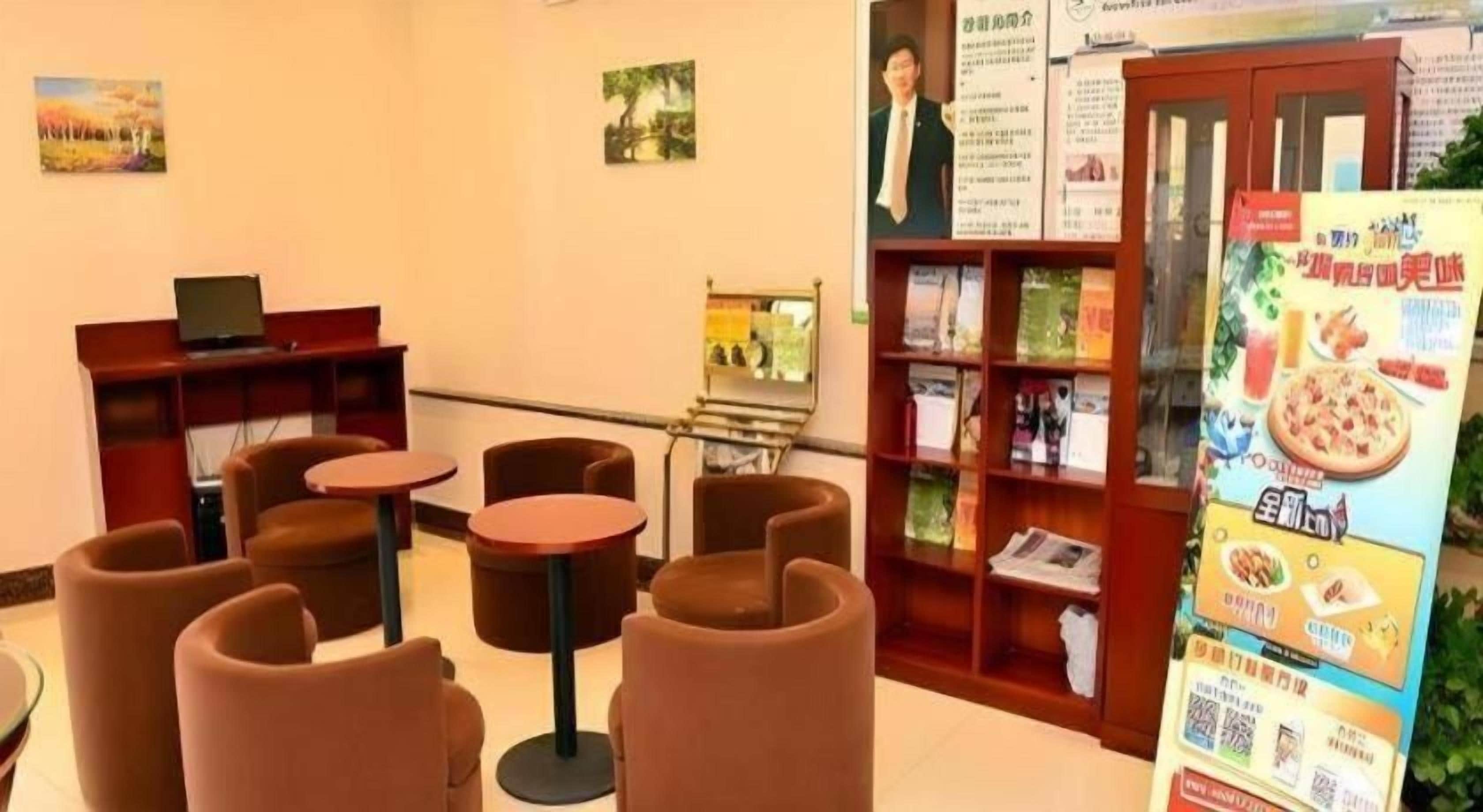 A hotel lobby with seating arrangements, a reception desk, informational posters, and a menu board.