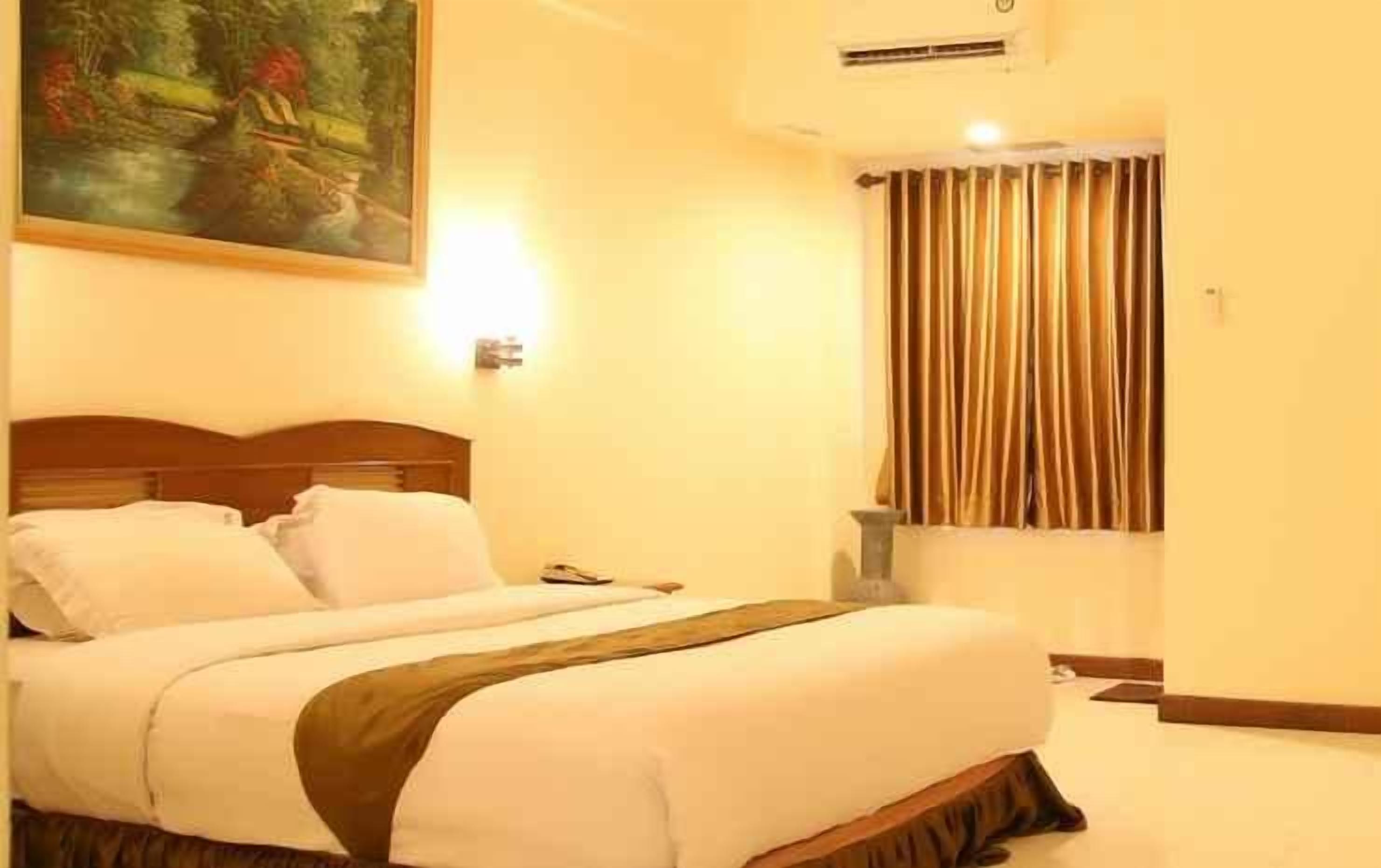 A hotel room with a bed, a painting on the wall, a window with curtains, and a bedside table.