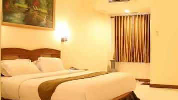 A hotel room with a bed, a painting on the wall, a window with curtains, and a bedside table.