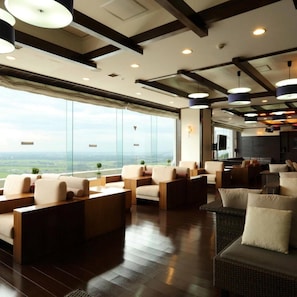 Amplia sala de estar con diversas opciones de asientos, ventanas grandes que ofrecen vistas del paisaje y un diseño de techo moderno.
