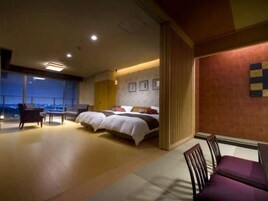 A hotel room with a large bed, a seating area, and a view of the city.
