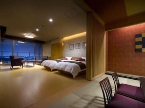 Habitación de hotel con una cama grande, zona de estar y vistas a la ciudad.