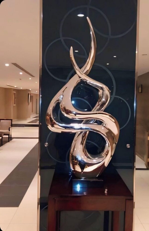 En modern skulptur i en entréhall med en glasvägg och en träplattform.
