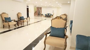 En hotelllobby med ett välpolerat golv, en sittgrupp med stolar och soffor och en trappa i bakgrunden.