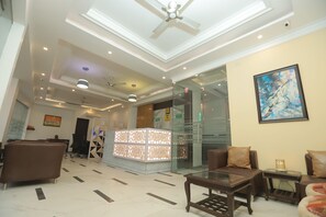 A hotel lobby with seating, a reception desk, and a ceiling fan.
