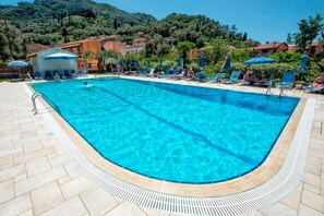 A clear blue swimming pool with lounge chairs and umbrellas, surrounded by buildings and greenery. - Nobile Boutique Hotel (Corfu)