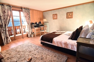 Quarto com cama, escrivaninha e cadeira. É possível ver o exterior pela janela.