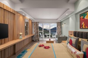 Ein Hotelzimmer mit Bett, Fernseher, einem Balkon mit Bergblick und einer Essecke.