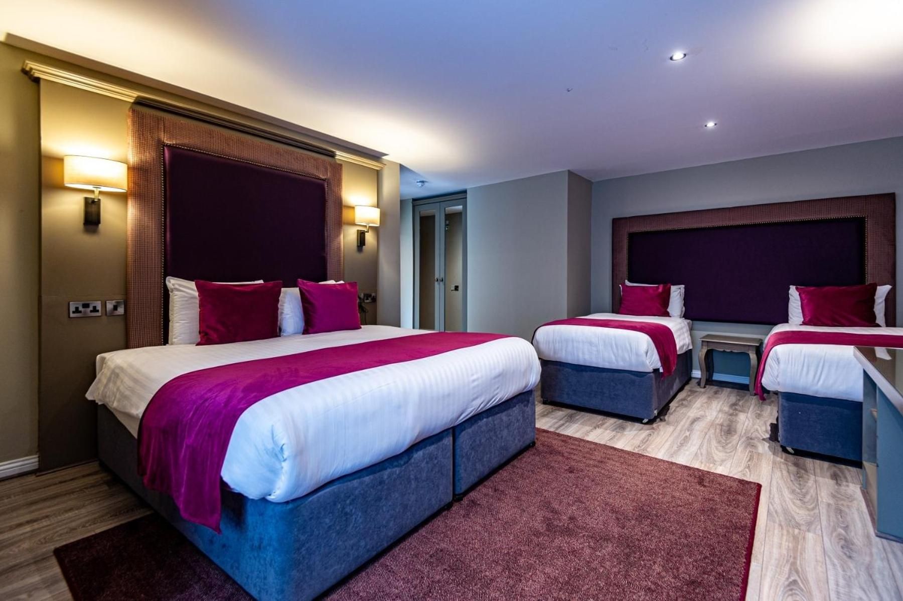 A hotel room with two beds, a small table, and a wardrobe.