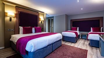 A hotel room with two beds, a small table, and a wardrobe.