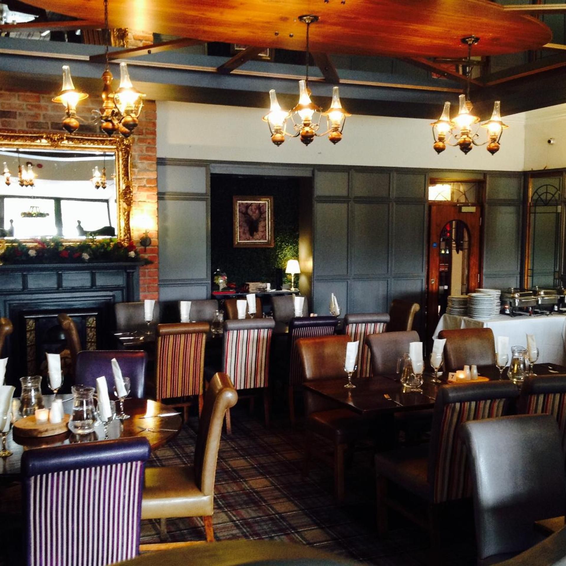 A restaurant interior with multiple tables, chairs, and hanging light fixtures.