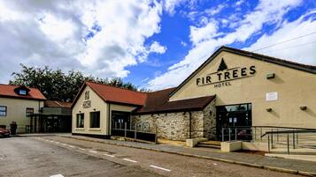 A hotel named 'FIR TREES' with a stone facade and a red-tiled roof.
