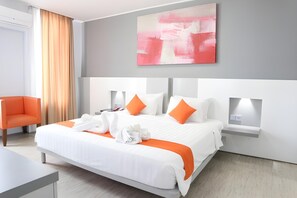 A modern hotel room with a large bed, orange accents, and a painting on the wall. - Grand Nanggroe (Banda Aceh)