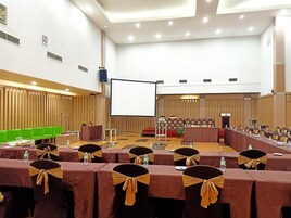 A conference room with rows of tables, chairs, and a stage area.