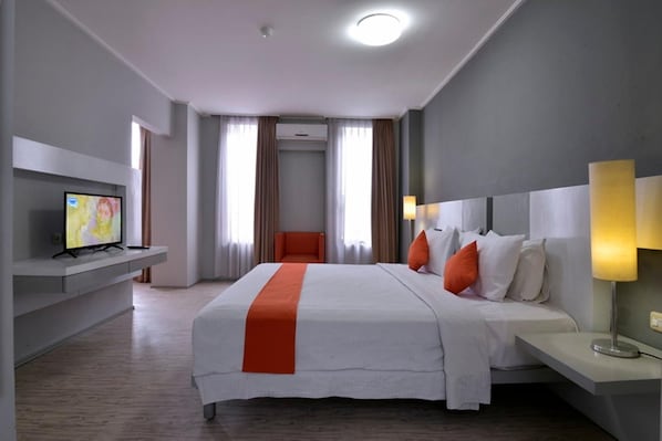 A hotel room with a bed, a TV, a chair, and a desk.