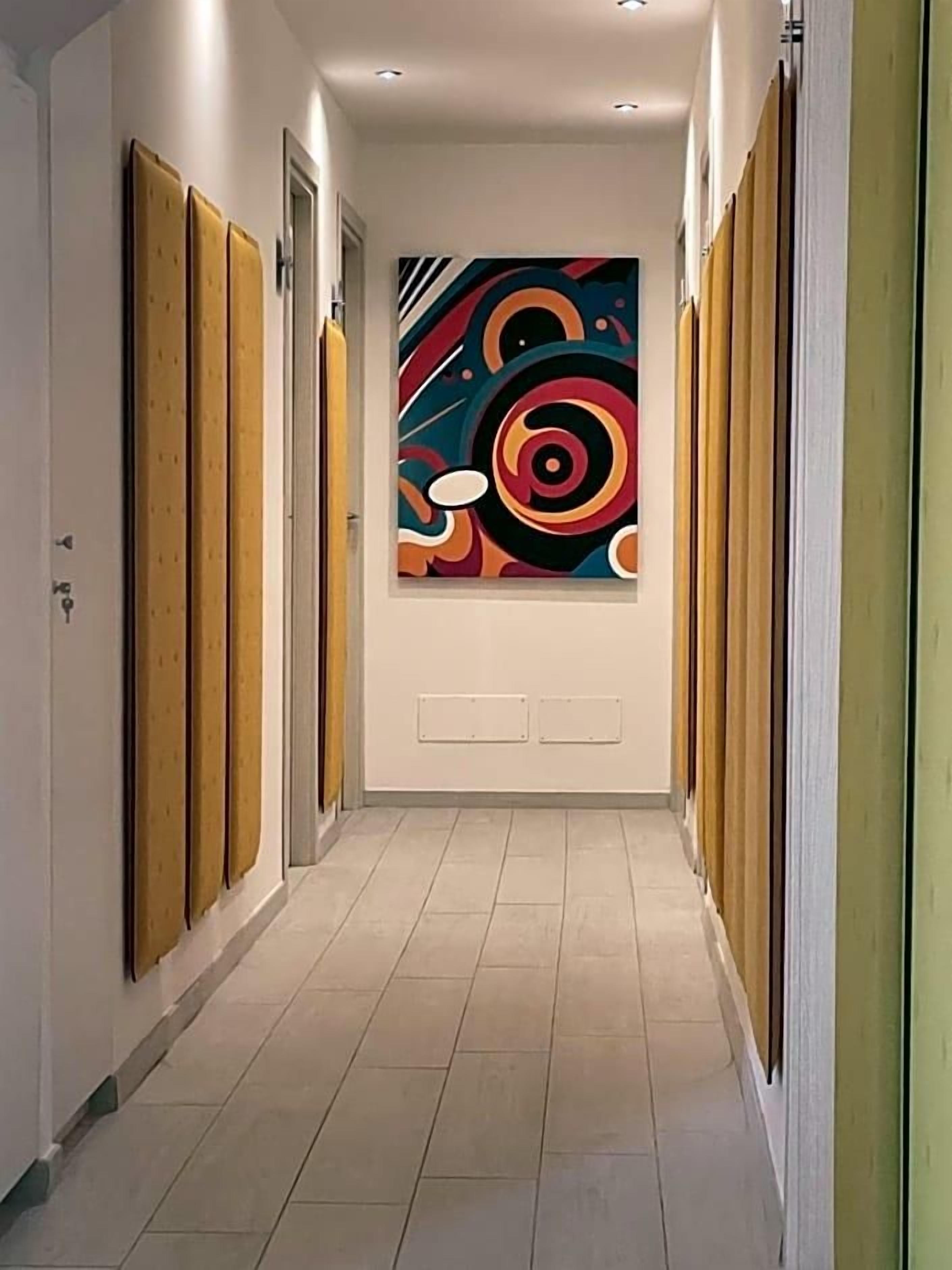 A hallway with a modern design, featuring a colorful abstract painting on the wall and wooden paneling on the walls.