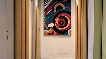 A hallway with a modern design, featuring a colorful abstract painting on the wall and wooden paneling on the walls.