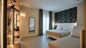 Een hotelkamer met twee bedden, een kledingkast, een spiegel en een wand met bloemenprint.