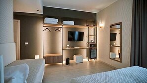 Een hotelkamer met een bed, een televisie, een kledingkast, een spiegel en een zithoek.