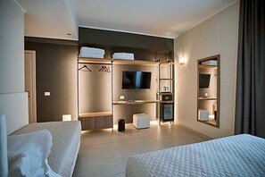 A hotel room with a bed, a TV, a wardrobe, a mirror, and a small seating area. - Castrichella Boutique Hotel (Fiumicino)