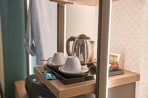 A hotel room's kitchenette with a coffee maker, cups, and a box of tea. - Castrichella Boutique Hotel (Fiumicino)