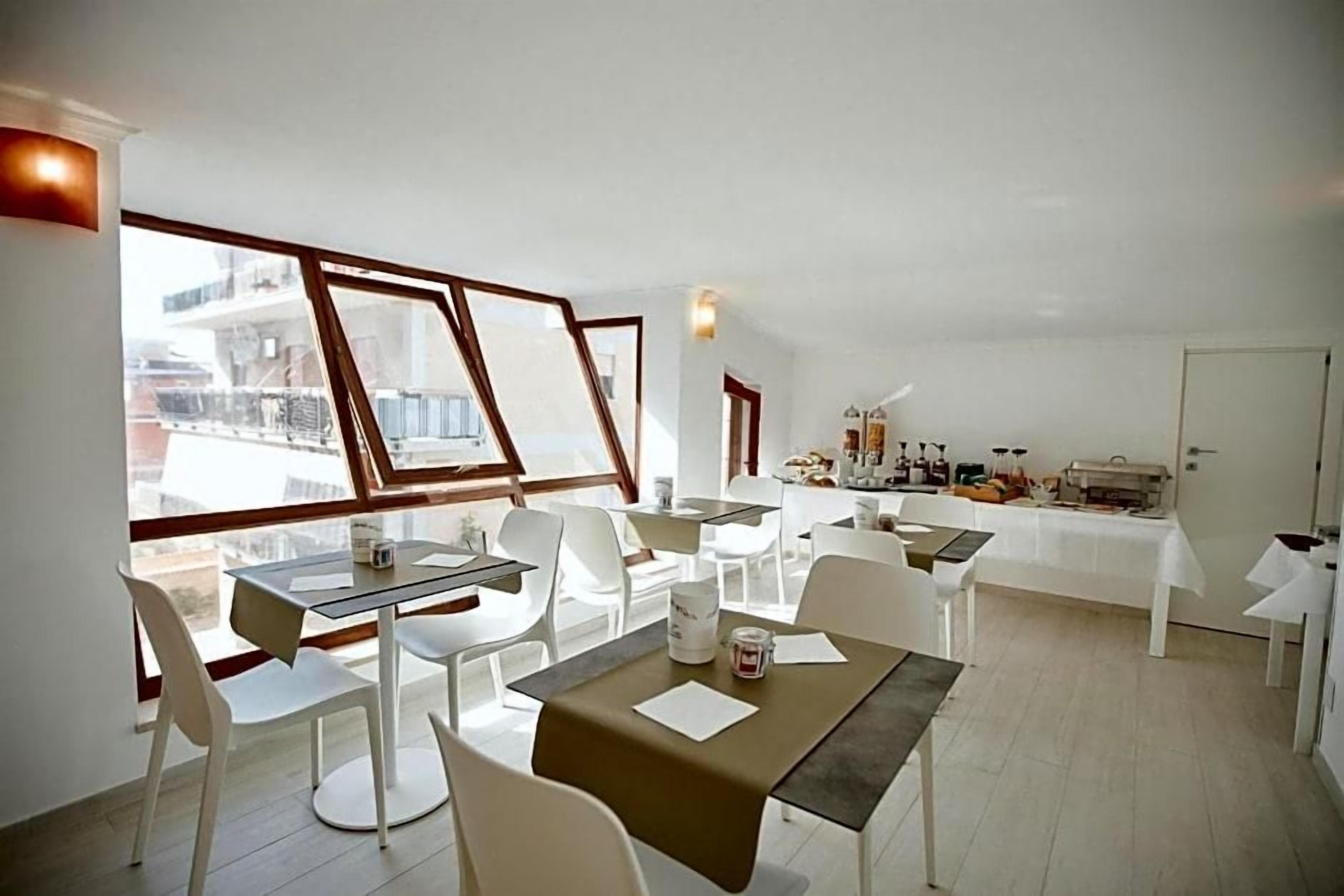 A dining area with tables and chairs, a buffet setup, and large windows offering a view of the city.