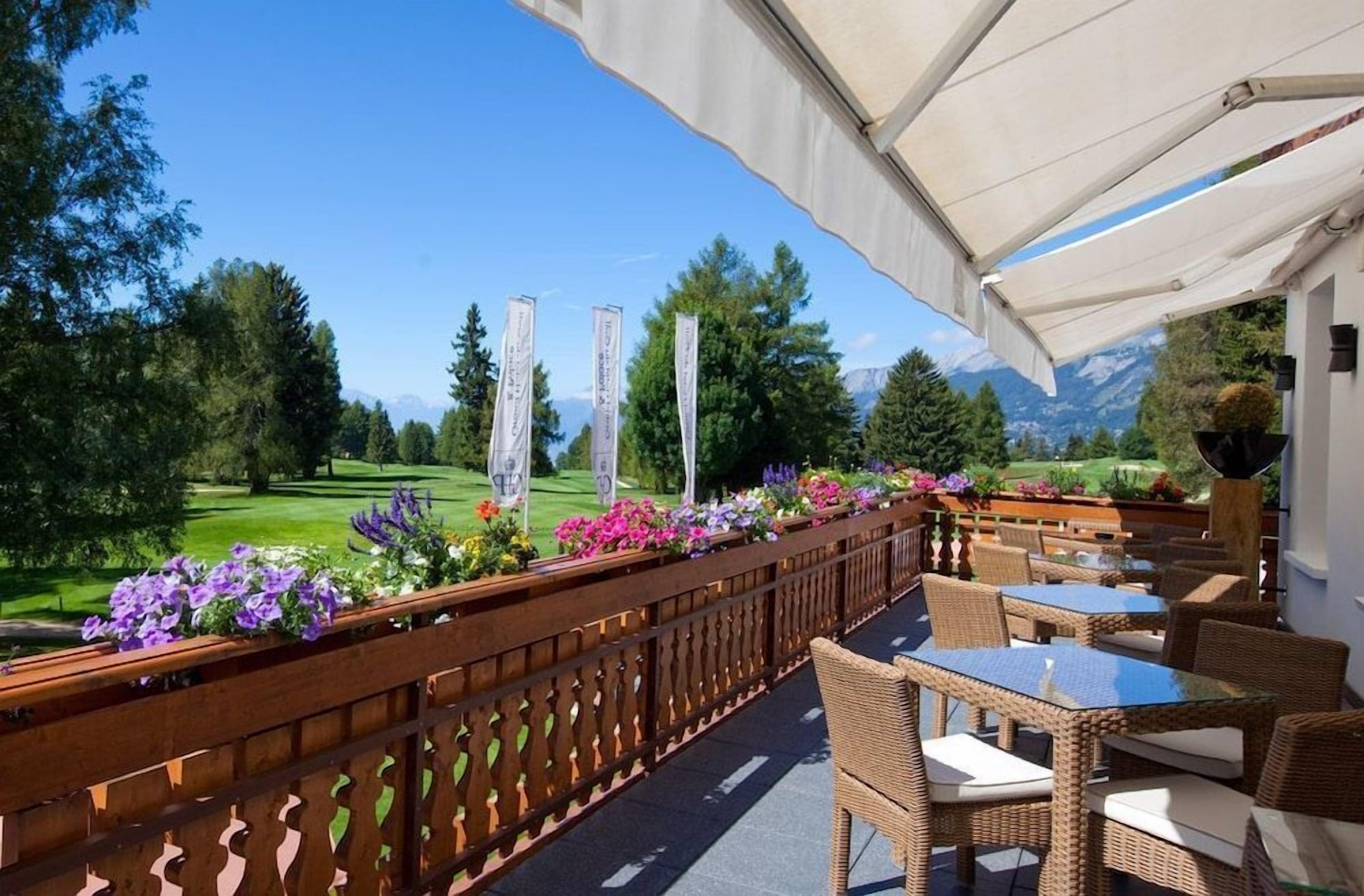 An outdoor seating area with wicker furniture and a view of a golf course.