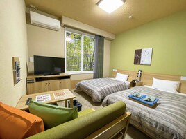 Habitación de hotel con dos camas, un televisor, una mesita con un menú y una ventana con vistas a árboles.