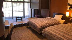 Habitación de hotel con dos camas, televisión, una mesita y vistas al exterior.