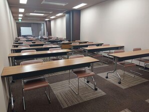 Un aula con filas de escritorios y sillas, suelo alfombrado y una pizarra al frente.