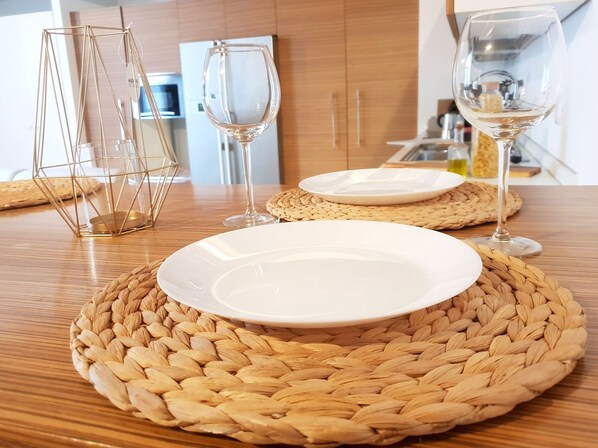 A dining table with two white plates, two clear wine glasses, and a geometric glass candle holder. - Design Central Apartment (Bergamo)