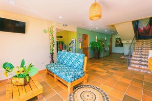 A living room with a sofa, a coffee table with a plant, a television, and a staircase leading to an upper level. - Hotel Bambu Guatape (Guatapé)