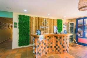 A reception desk with a bamboo backdrop and a green wall. - Hotel Bambu Guatape (Guatapé)