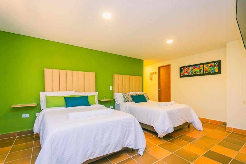 A room with two beds, green walls, and a colorful painting.