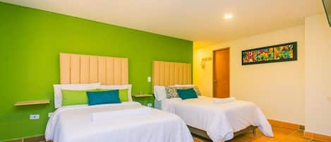 A room with two beds, green walls, and a colorful painting.