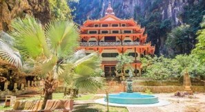 A traditional multi-tiered building with a circular water feature in front.
