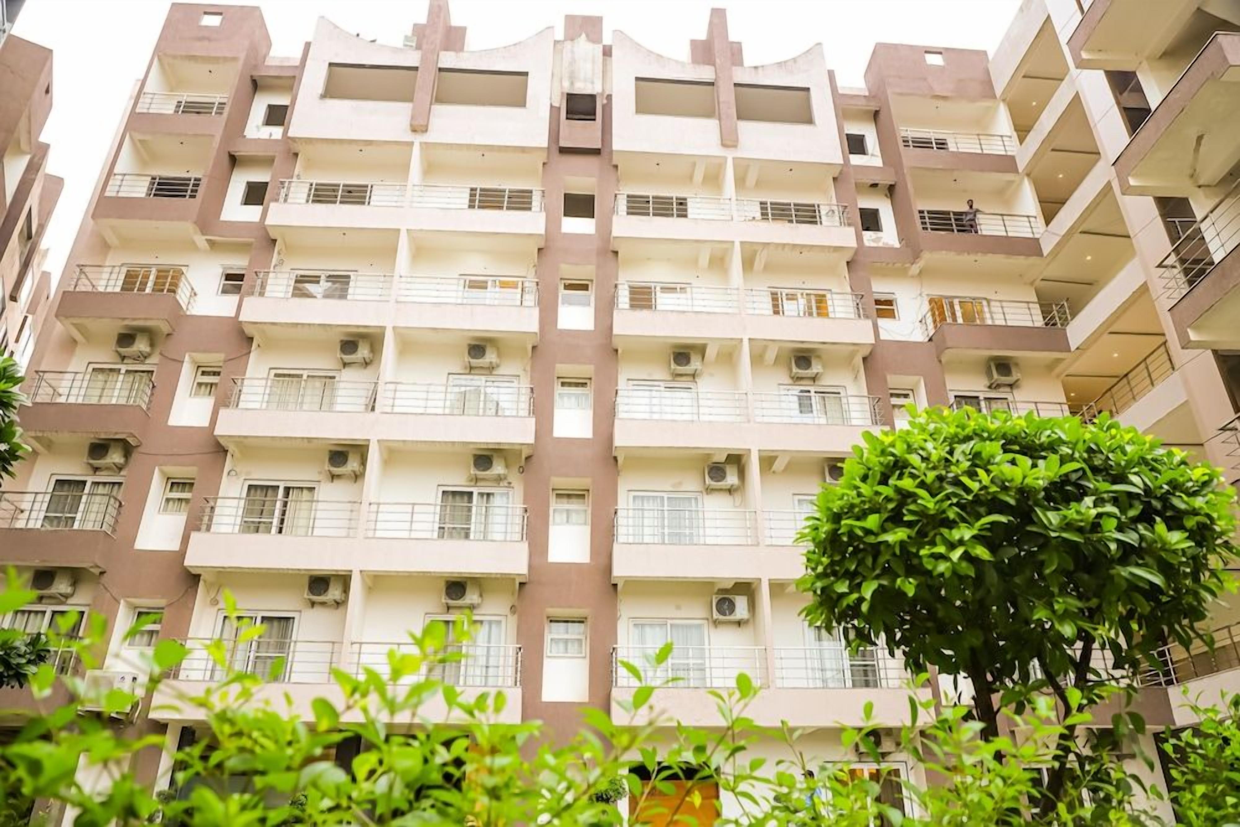 A multi-story residential building with balconies, air conditioning units, and a central staircase.
