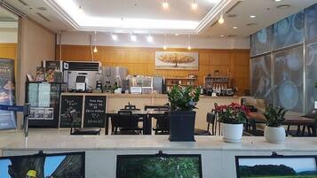A modern cafe interior with a counter, seating area, and large windows.