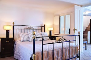 Quarto com cama, mesas de cabeceira, luminárias, espelho e escada.