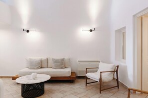Ein modernes Wohnzimmer mit einer Couch, einem Sessel, einem Couchtisch und zwei Wandleuchten.