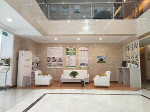 Vestíbulo con mostrador de recepción, zona de estar y escalera.