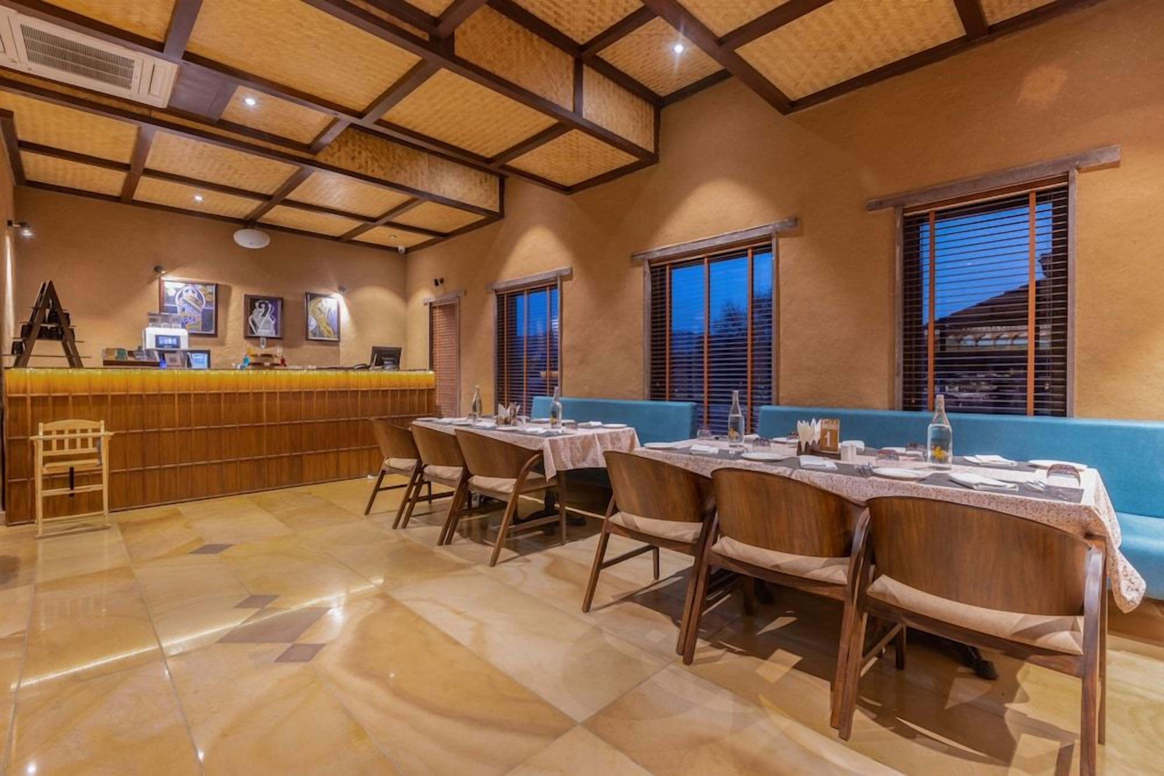 A restaurant with a bar area, wooden chairs, and a blue bench.
