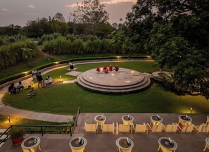 A landscaped outdoor area with a circular seating arrangement and a tiered seating area with tables and chairs.