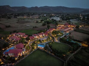 Un resort con varias edificaciones, una piscina y un paisaje bien iluminado.
