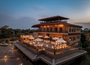 Un hotel de varios pisos con mesas al aire libre y una terraza cubierta.