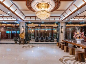 Um hall amplo com um grande candelabro, área de estar e balcão de recepção.